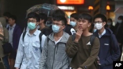 Youths wearing face masks to protect against the spread of the new coronavirus walk on a street in Taipei, Taiwan, March 30, 2020.