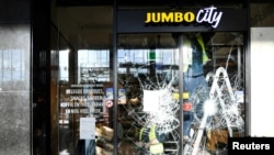 Glaziers remove broken glass at a supermarket after yesterday's riots against the COVID-19 lockdown in Eindhoven, Netherlands January 25, 2021. REUTERS/Piroschka van de Wouw