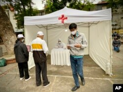 People receive test results at a makeshift COVID-19 testing facility in Hanoi, Vietnam on Tuesday, Mar.31, 2020. Vietnam has set up its first makeshift facilities for fast coronavirus testing in residential areas in an effort to detect early infections.
