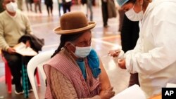 A woman gets a shot of the Sinopharm COVID-19 vaccine during vaccinations of people over age 40 inside the gym of the American Institute school in La Paz, Bolivia, June 4, 2021.