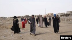 FILE - Displaced people leave al-Hud village, south of Mosul, during an operation to attack Islamic State militants in Mosul, Iraq, Oct. 18, 2016. Residents of al-Hud rose up against IS militants.