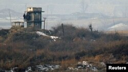North Korean soldiers watch the South Korean side from a lookout tower at their observation post in the demilitarized zone (DMZ) separating the two Koreas, December 28, 2011. 
