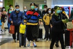 Passengers protective wear face masks as they arrive from Shenzhen to Hong Kong at Lo Wu MTR station hours before the closing of the Lo Wu border crossing in Hong Kong, Feb. 3, 2020.