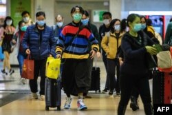 Passengers protective wear face masks as they arrive from Shenzhen to Hong Kong at Lo Wu MTR station hours before the closing of the Lo Wu border crossing in Hong Kong, Feb. 3, 2020.