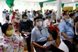 Orang-orang yang memakai masker pelindung duduk mengantre sebelum menerima dosis vaksin Sinovac, selama vaksinasi massal untuk lansia di Jakarta, 2 Maret 2021. (Foto: Reuters)