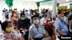 People wearing protective masks sit as they queue before receiving a dose of China's Sinovac Biotech vaccine, during mass vaccination for elderly people in Jakarta, Indonesia, March 2, 2021. 
