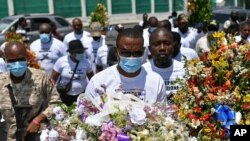 Pierre Gary Bernadotte, miembro del partido político PHTK del presidente asesinado, lleva flores a un lugar fuera del palacio presidencial en memoria del difunto presidente Jovenel Moise en Puerto Príncipe, Haití, el miércoles 14 de julio de 2021.