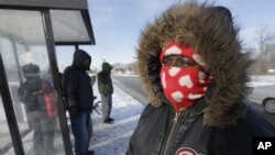 Protegiéndose del frio en una parada de autobús, en Chicago.