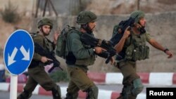 Tentara Tentara Israel berlari dekat lokasi tempat seorang pria palestina ditembak di Hebron, Tepi Barat yang dikuasai, 3 September 2018. Menurut tentara Israel, pria itu mencoba menikam seorang tentara.