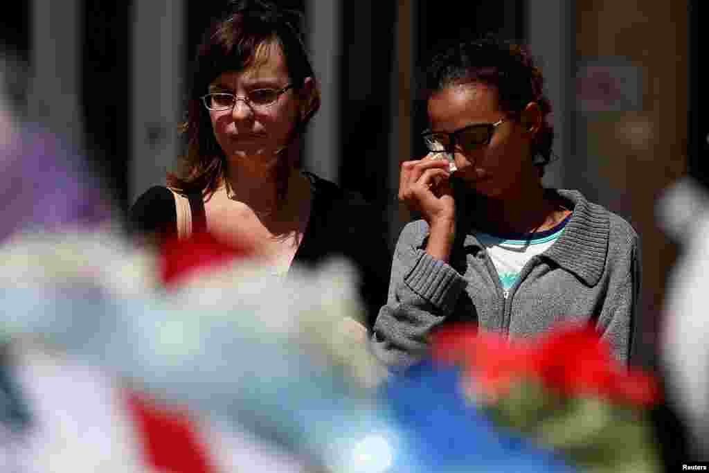 Ginny Alexander (R) wipes a tear as she and her mother Ariel Alexander stand behind a police car that makes up part of a makeshift memorial at police headquarters following the multiple police shooting in Dallas, Texas, July 8, 2016. 