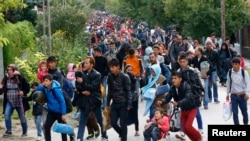 FILE - Migrants carry their belongings as they walk towards the Austrian border from Hegyeshalom, Hungary, Sept. 24, 2015. 