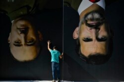A man sets up upside down giant paintings of late Spanish dictator Francisco Franco, left, and Spanish King Felipe VI ahead of a protest in support of Catalonia's independence movement, in Bilbao, northern Spain, Oct. 15, 2019.