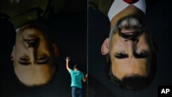 A man sets up upside down giant paintings of late Spanish dictator Francisco Franco, left, and Spanish King Felipe VI ahead of a protest in support of Catalonia's independence movement, in Bilbao, northern Spain, Oct. 15, 2019. 