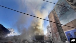 Smoke rises near a giant portrait of the late Hezbollah military commander Imad Mughniyeh after a building was hit by an Israeli airstrike in Dahiyeh, a southern suburb of Beirut, Lebanon, Oct. 20, 2024.