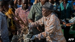 FILE - Tanzanian President John Magufuli joins a cleanup event outside the State House in Dar es Salaam on Dec. 9, 2015. Magufuli canceled Independence Day celebrations and ordered a national day of cleanup instead.