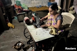 Reena Ben works on a solar-powered sewing machine to stitch clothes inside her one-room house in Modhera, India's first round-the-clock solar-powered village, in the western state of Gujarat, India, October 19, 2022. (REUTERS/Sunil Kataria)