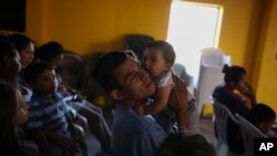 Jose, 31, from Guatemala, holds his infant daughter during a church service at the Agape World Mission shelter, where many Central American and Mexican migrants stay while trying to reach the U.S. or request asylum, in Tijuana, Mexico, Sept. 12, 2019. 