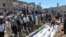La gente se reúne alrededor de los cádaveres de las víctimas de un bombardeo de las fuerzas sirias en Houla, en el que murieron 108 personas. Decenas más habrían muerto este lunes en nuevos ataques.