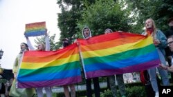 FILE – LGBTQ+ activists wave flags at a rally in Moscow on July 15, 2020. 