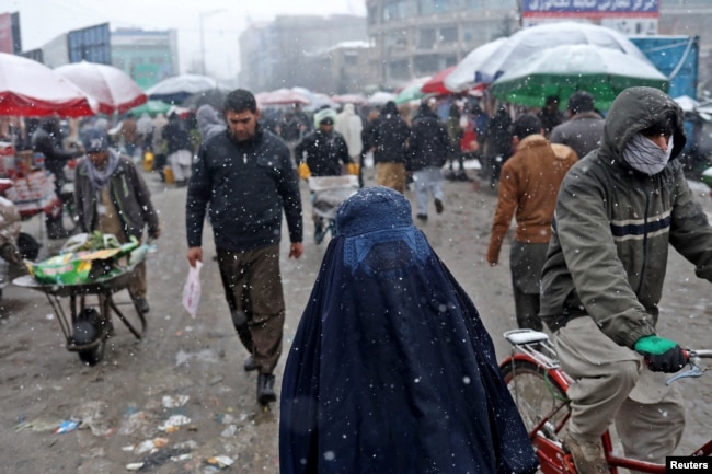 FILE - An Afghan woman walks on the street during a snowfall in Kabul, Jan. 3, 2022.