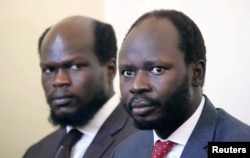 Kerbino Wol, left, a businessman, and Peter Biar Ajak, the South Sudan country director for the London School of Economics International Growth Center based in Britain, sit in the dock inside the courtroom in Juba, South Sudan, June 11, 2019.