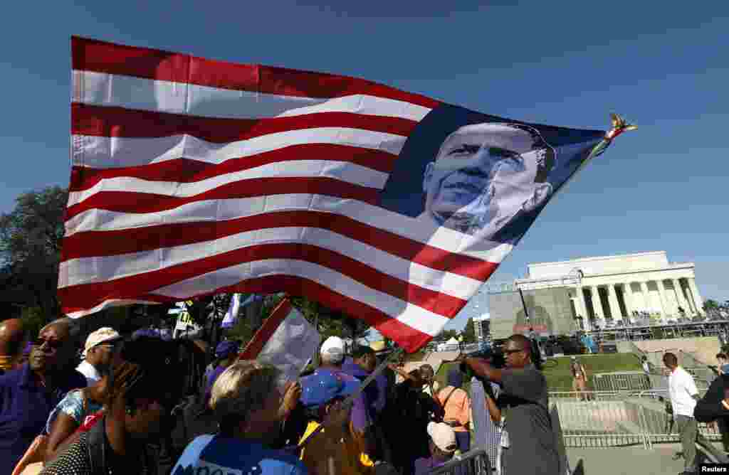 Seorang peserta pawai memegang bendera AS bergambar Presiden Barack Obama (24/8). (Reuters/Kevin Lamarque)