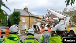 Para petugas tengah menyingkirkan pohon yang rubuh di Jalan Bath di Hounslow, London barat (28/10). 