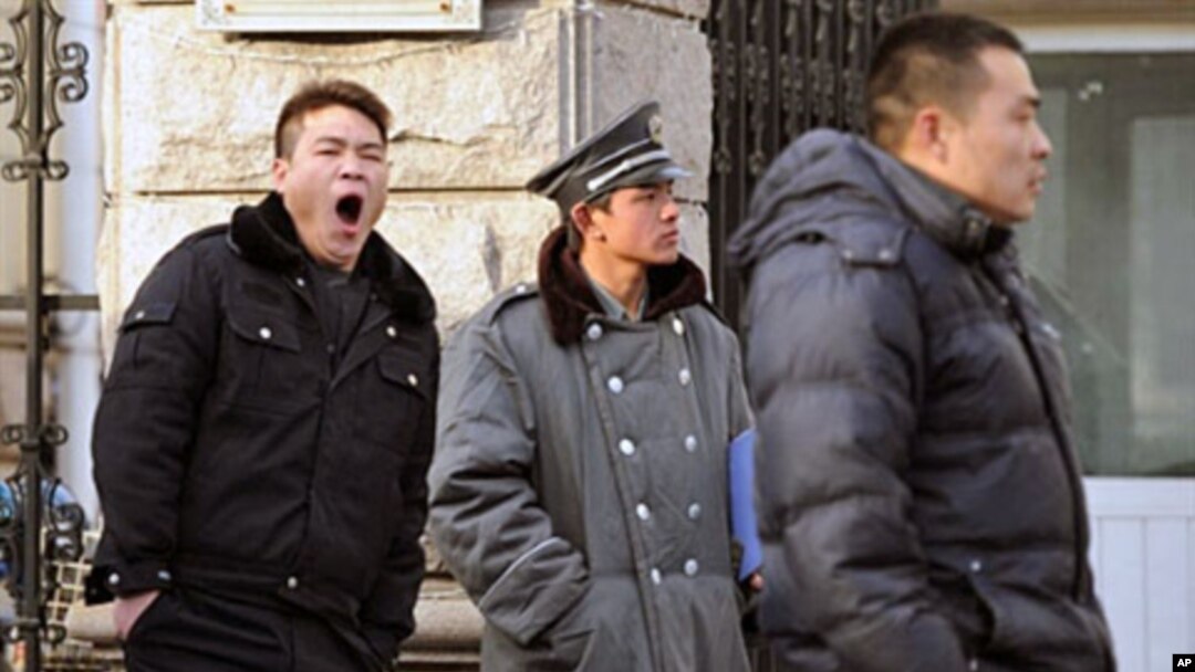Plainclothes policemen (L and R) keep watch outside the house of jailed Chinese dissident Liu Xiaobo, the 2010 Nobel Peace Prize winner, in Beijing on 08 Dec 2010