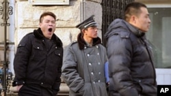 Plainclothes policemen (L and R) keep watch outside the house of jailed Chinese dissident Liu Xiaobo, the 2010 Nobel Peace Prize winner, in Beijing on 08 Dec 2010