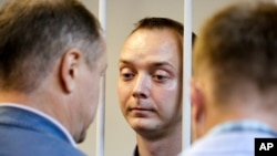 FILE - Ivan Safronov, an adviser to the director of Russia's state space corporation, stands behind bars in a courtroom in Moscow, Russia, July 7, 2020.