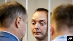 FILE - Ivan Safronov, an adviser to the director of Russia's state space corporation, stands behind bars in a courtroom in Moscow, Russia, July 7, 2020.
