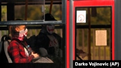 People wearing a face mask sit in a bus in Belgrade, Serbia, Friday, May 8, 2020. (AP Photo/Darko Vojinovic)