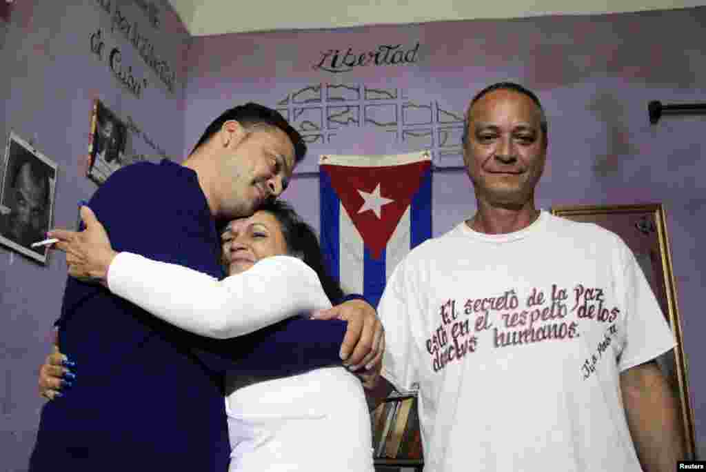 Angel Figueredo (right) stands next to his wife Haydee Gallardo who hugs their son Reynier at their home. Figueredo and Gallardo, members of the "Ladies in White" dissident group, are among eight detainees who were freed on this day, Havana, Cuba, Jan. 8, 2015.