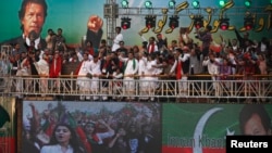 Supporters of Imran Khan (on screens top and R), chairman of the opposition Pakistan Tehreek-e-Insaf (PTI) political party, chant anti-government slogans during his speech at a rally in Karachi September 21, 2014. Protesters led by Imran Khan, a former cricket star, and Tahir ul-Qadri, a firebrand cleric, have been locked in a bitter stand-off with the government since mid-August. (REUTERS/Akhtar Soomro)