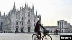 Une personne portant un masque fait du vélo sur la place du Duomo, dans la Lombardie en Italie, après que le gouvernement a introduit de nouvelles mesures restrictives en raison d'une hausse du nombre d'infections par le COVID-19, Italie 19 octobre 2020. REUTERS/Flavio Lo Scalzo