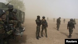 Cameroonian soldiers stand guard amidst dust kicked up by a helicopter in Kolofata, March 16, 2016. Hit hard by Boko Haram, Benin, Cameroon, Chad, Niger, and Nigeria have put together a regional force to try to wipe out the militant group.