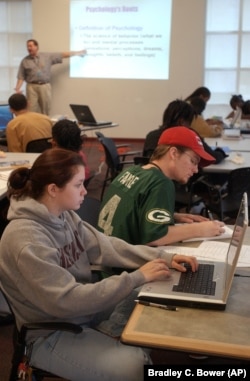 Harrisburg University student Kelsey Collins, foreground, works on a computer which is wirelessly connected to her professor's laptop presentation data.