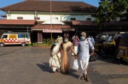 Indians wearing surgical masks walk out of the government general hospital where a student who had been in Wuhan is kept in isolation in Thrissur, Kerala state, Jan. 30, 2020.