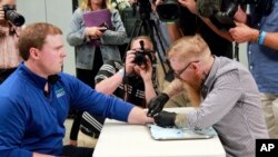 Tony Danna, left, vice president of international development at Three Square Market in River Falls, Wis., receives a microchip in his left hand at company headquarters, Aug. 1, 2017. The company is making microchips available to its employees, allowing them to open doors, log onto their computers or buy breakroom snacks by simply waving their hands.