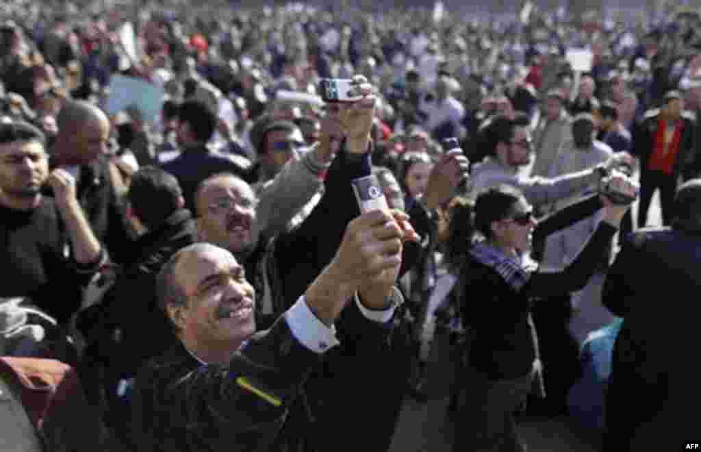 Egyptian anti-government protesters take photos of one of the many and colorful placards with their camera phones at the continuing demonstration in Tahrir square in downtown Cairo, Egypt, Monday, Jan. 31, 2011. A coalition of opposition groups called for