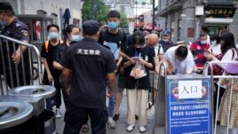 People scan health check codes with their smartphones to show to a security guard at a tourist shopping street in Beijing, Tuesday, Aug. 3, 2021. (AP Photo/Mark Schiefelbein)