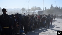 Migrants and refugees wait in a queue to be allowed to pass from the northern Greek village of Idomeni to southern Macedonia, Nov. 9, 2015. 