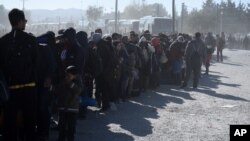 Migrants and refugees wait in a queue to be allowed to pass from the northern Greek village of Idomeni to southern Macedonia, Nov. 9, 2015. 