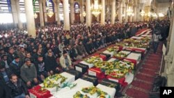 Men pray next to the coffins of people killed at security sites on Friday in two car bomb attacks, at the Umayyad Mosque in Damascus, Syria, December 24, 2011.