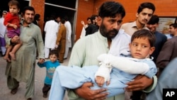 A man carries a child injured from an earthquake, in Peshawar, Pakistan, Oct. 26, 2015.