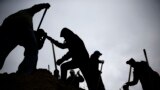 Against a gray winter sky, volunteers use shovels atop a pile of sand as they help fill sandbags in St. Louis, Missouri, USA.