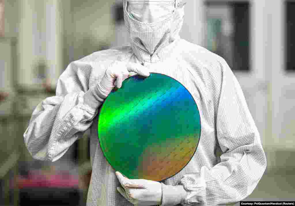 An employee of startup PsiQuantum holds a silicon disc containing the company's quantum computing chips at a facility in San Jose, California, in an undated handout photo provided on Feb. 25, 2025. 