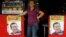 A woman stands in a restaurant between posters of Venezuela's President Hugo Chavez, in front of a military hospital, where Chavez is being treated, in Caracas, February 20, 2013.