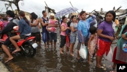 Những người sống sót xếp hàng chờ lãnh phẩm vật cứu trợ trên một con đường bị ngập nước tại thành phố Tacloban bị bão tàn phá, miền trung Philippines, ngày 12/11/2013.