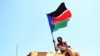 FILE - A man waves a South Sudanese flag in the town of Abyei, October 31, 2013. 